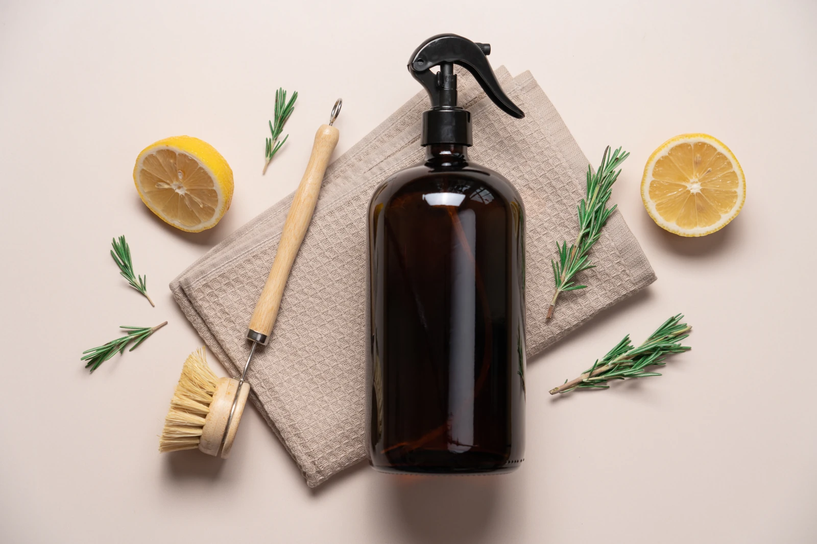 Braunglas-Putzmittelflasche mit Spülbürste und Zitronenhälften