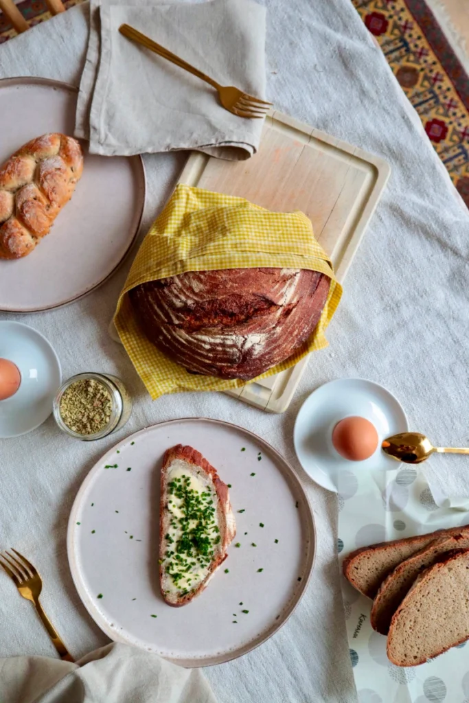 Brotlaib im gelb karierten Bienenwachstuch auf Frühstückstisch