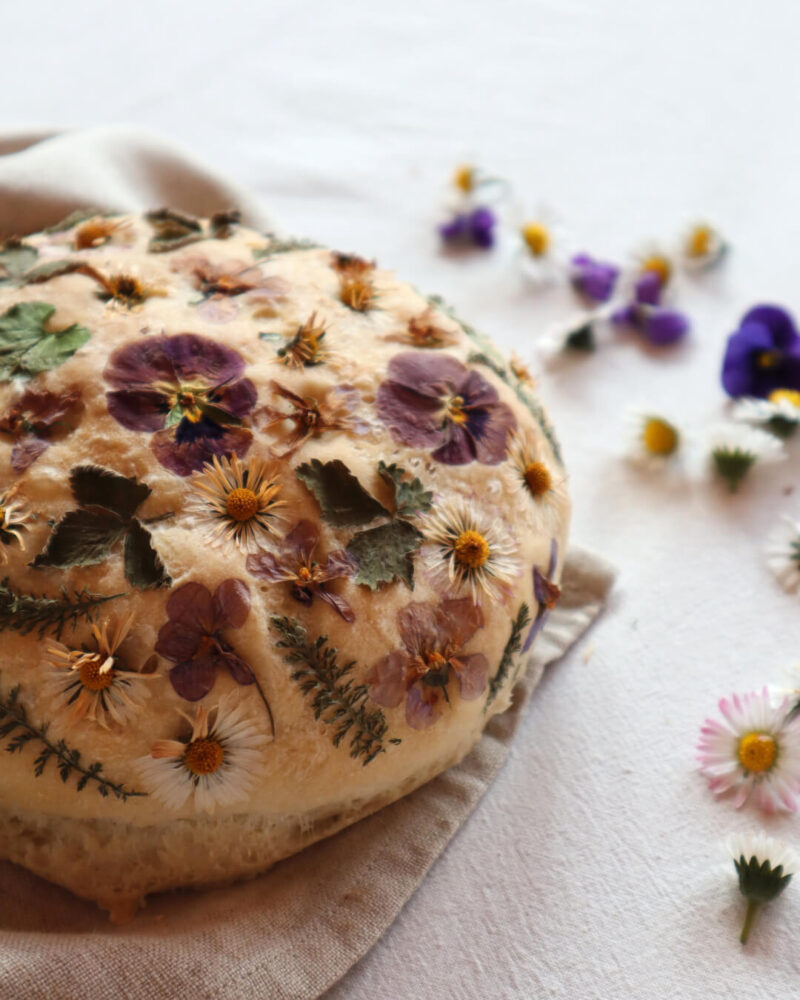 Mit Blüten und Kräutern belegter Brotlaib