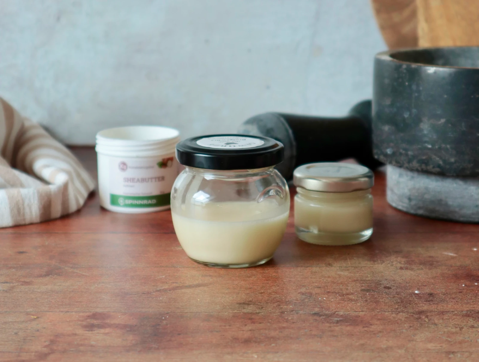 Deocreme mit Sheabutter im Glas, dahinter Gefäße