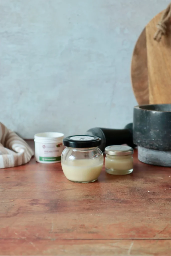 Deocreme mit Sheabutter im Glas, dahinter Gefäße