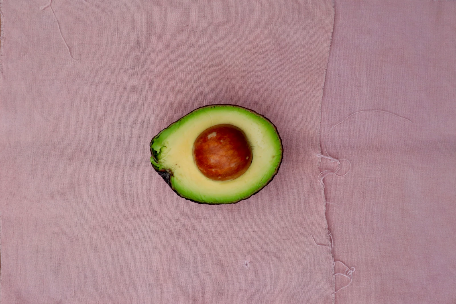 Avocadohälfte auf rosa Stoff