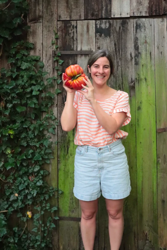 Katharina vor Holzwand mit großer Tomate