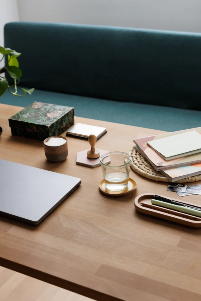 Schreibtisch mit Notizblock,Wasserglas und Laptop