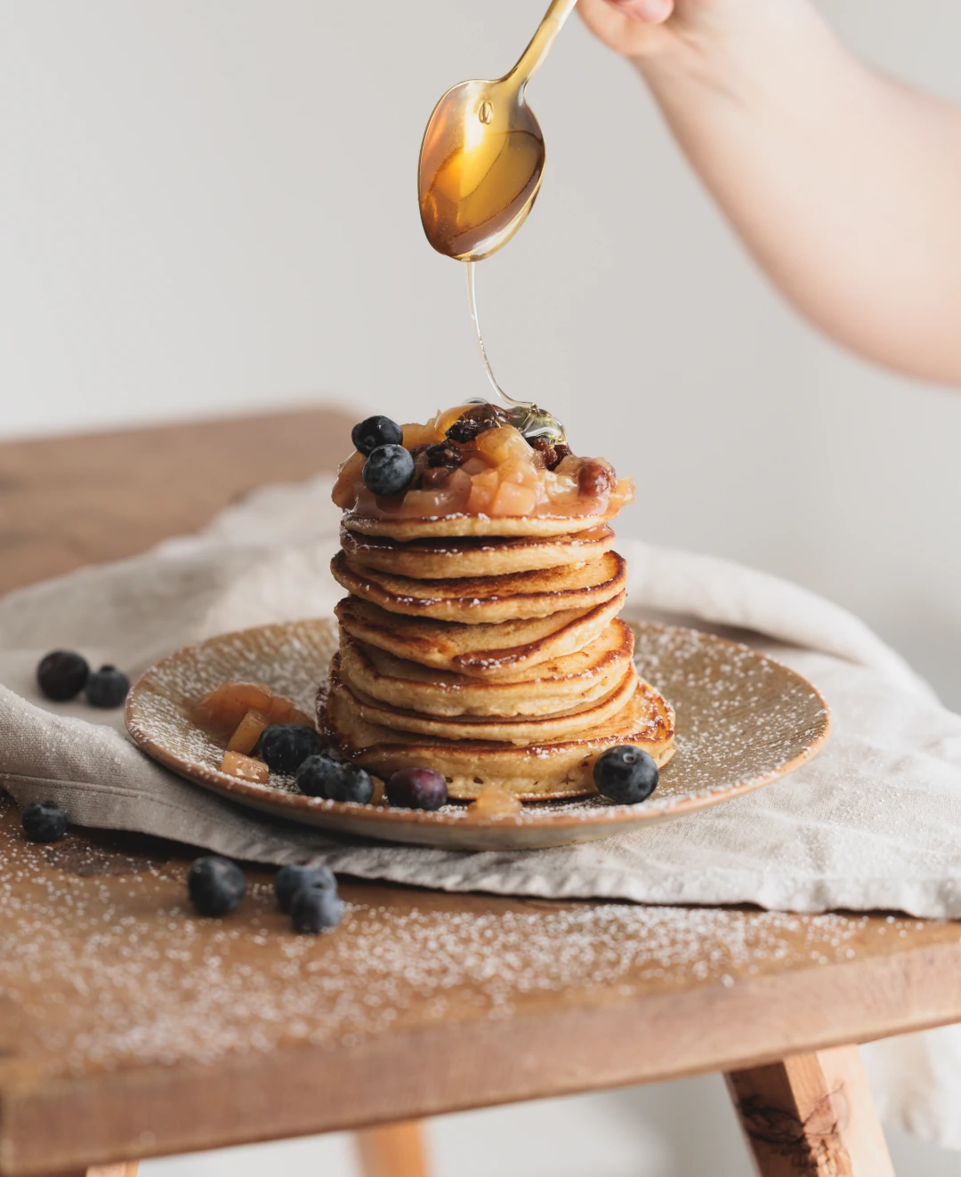 Ein Stapel Pancakes mit Honig und Blaubeeren